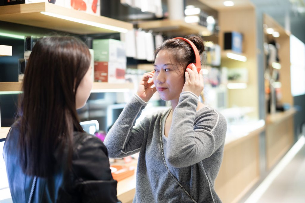 Asian teens listening to music on headphones.