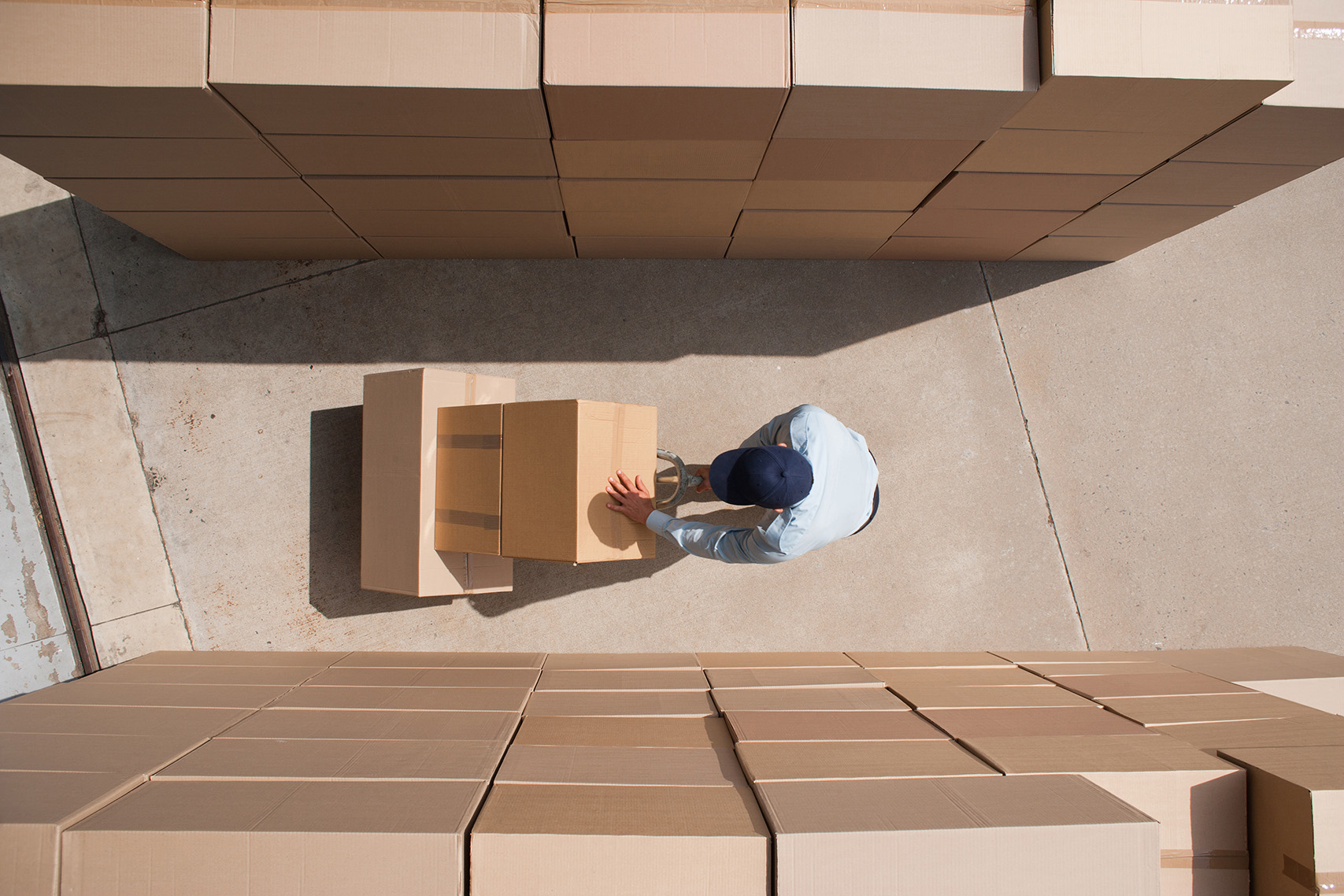 Worker standing with boxes and hand truck
