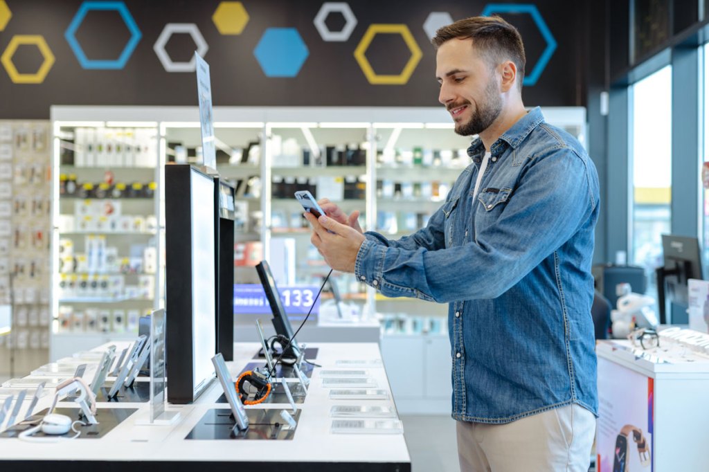 Man in a jean jacket in a mobile store looking at phones